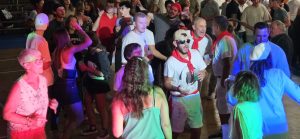 Ambiance festive sur la piste de danse lors d’une soirée années 80 animée par un DJ, public nombreux et éclairages colorés.