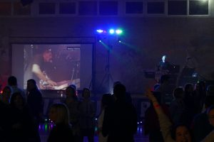 Installation DJ avec écran géant vidéo et animation musicale pendant une soirée dansante, public réuni devant la scène.