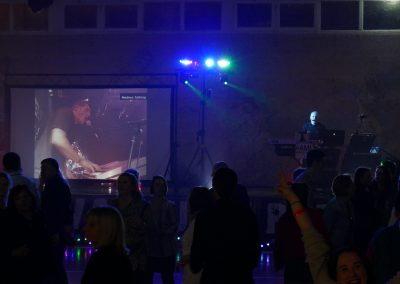 Installation DJ avec écran géant vidéo et animation musicale pendant une soirée dansante, public réuni devant la scène.
