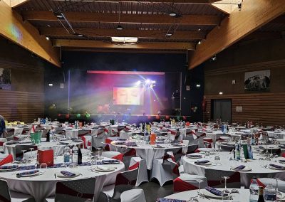 Installation DJ avec écran vidéo et éclairage scénique dans une grande salle des fêtes avant le début de la soirée.